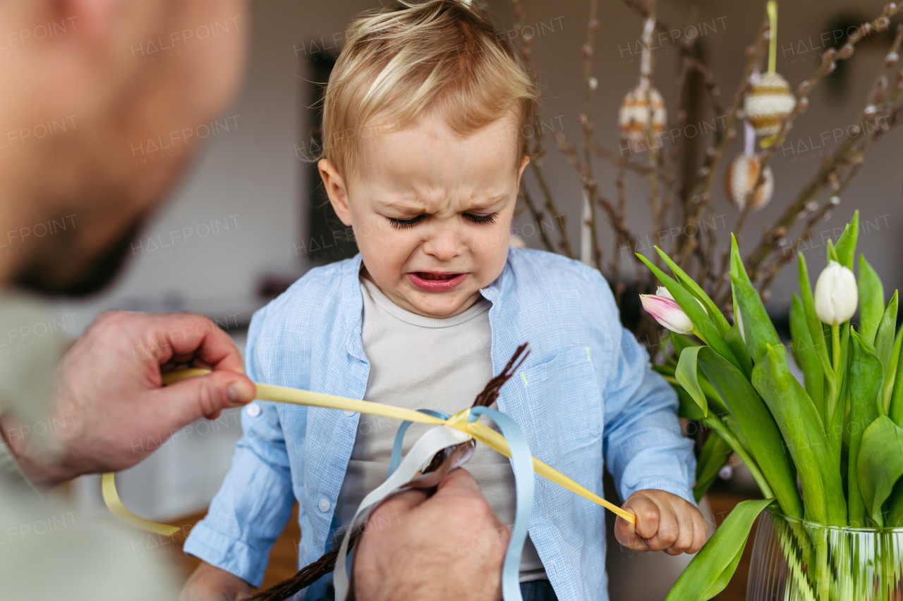 Father and little boy braiding easter whip from willow branches.