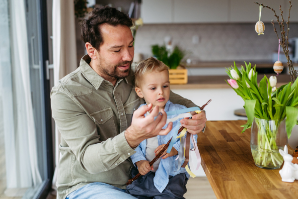 Father and little boy braiding easter whip from willow branches.