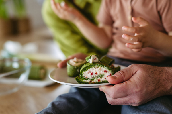 Close up of little boy eating green spinach roulade as a tradition on Easter Green Thursday.