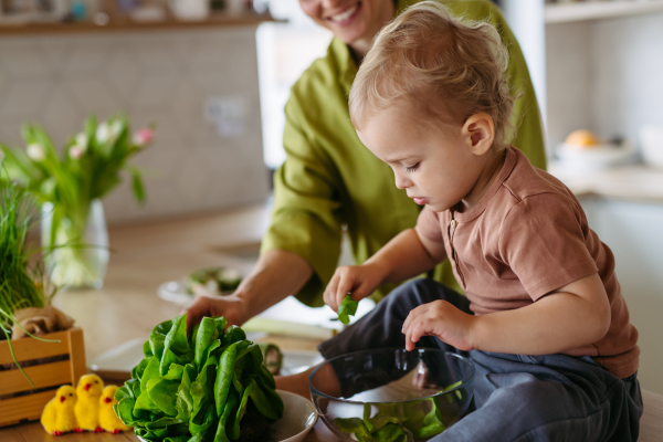 mom and little boy preparing lettuce salad to celebrate Easter Green Thursday. Green dish during Maundy thursday.