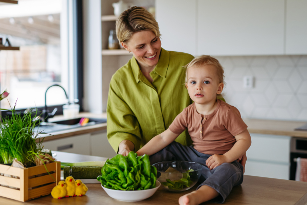 mom and little boy preparing lettuce salad to celebrate Easter Green Thursday. Green dish during Maundy thursday.