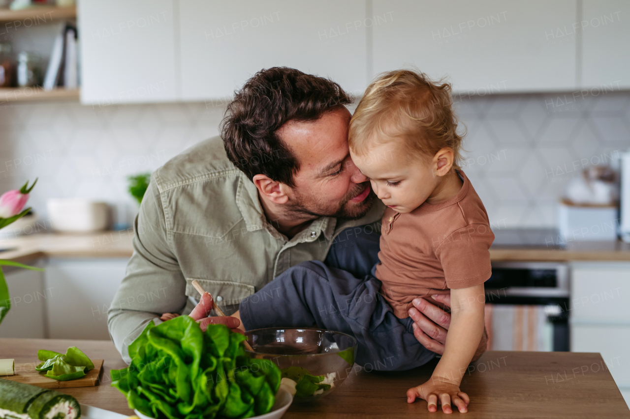 Dad and little boy preparing lettuce salad to celebrate Easter Green Thursday. Green dish during Maundy thursday.