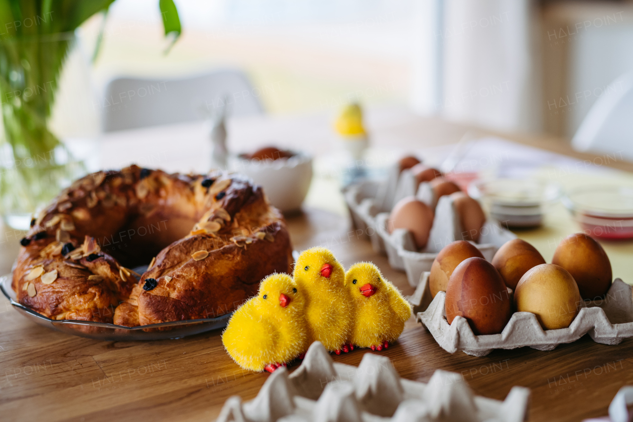 Traditional Easter table with dyed eggs, festive sweet bread, and decorative chicks.