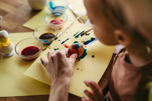 Close up of little boy painting eggs with brush and easter egg dye.