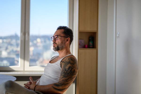 Portrait of handsome man with CGM sensor sitting at table at home.