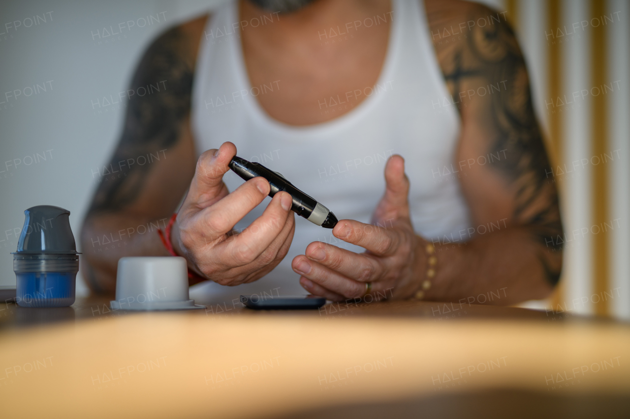 Diabetic man checking his blood sugar at home, using lancet to prick his finger for blood sample.