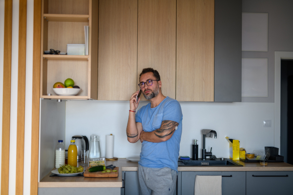 Diabetic man with CGM sensor standing in kitchen and making phone call.