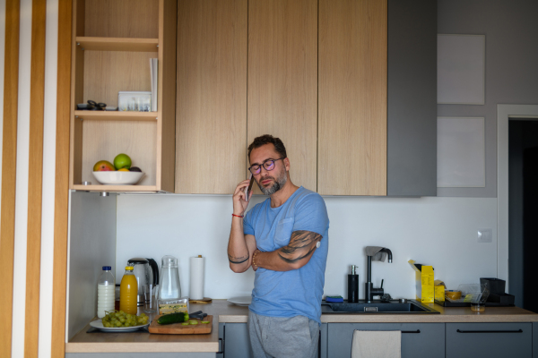 Diabetic man with CGM sensor standing in kitchen and making phone call.