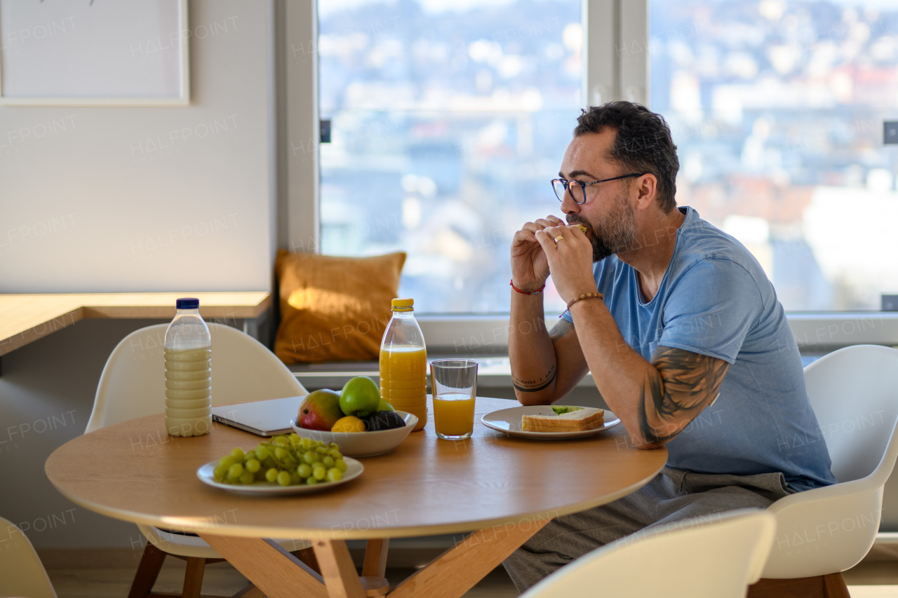 Diabetic man with CGM sensor having healthy breakfast, eating alone at table.