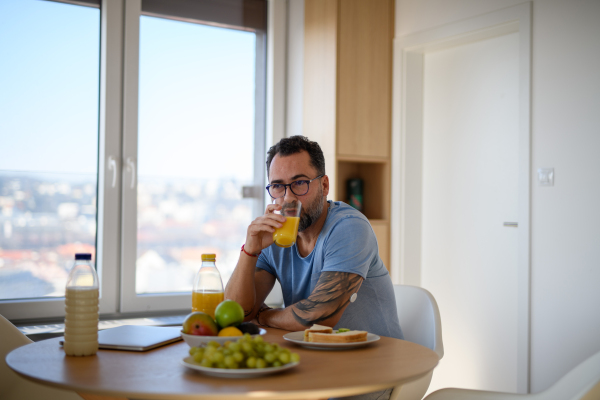 Diabetic man with CGM sensor having healthy breakfast, eating alone at table.