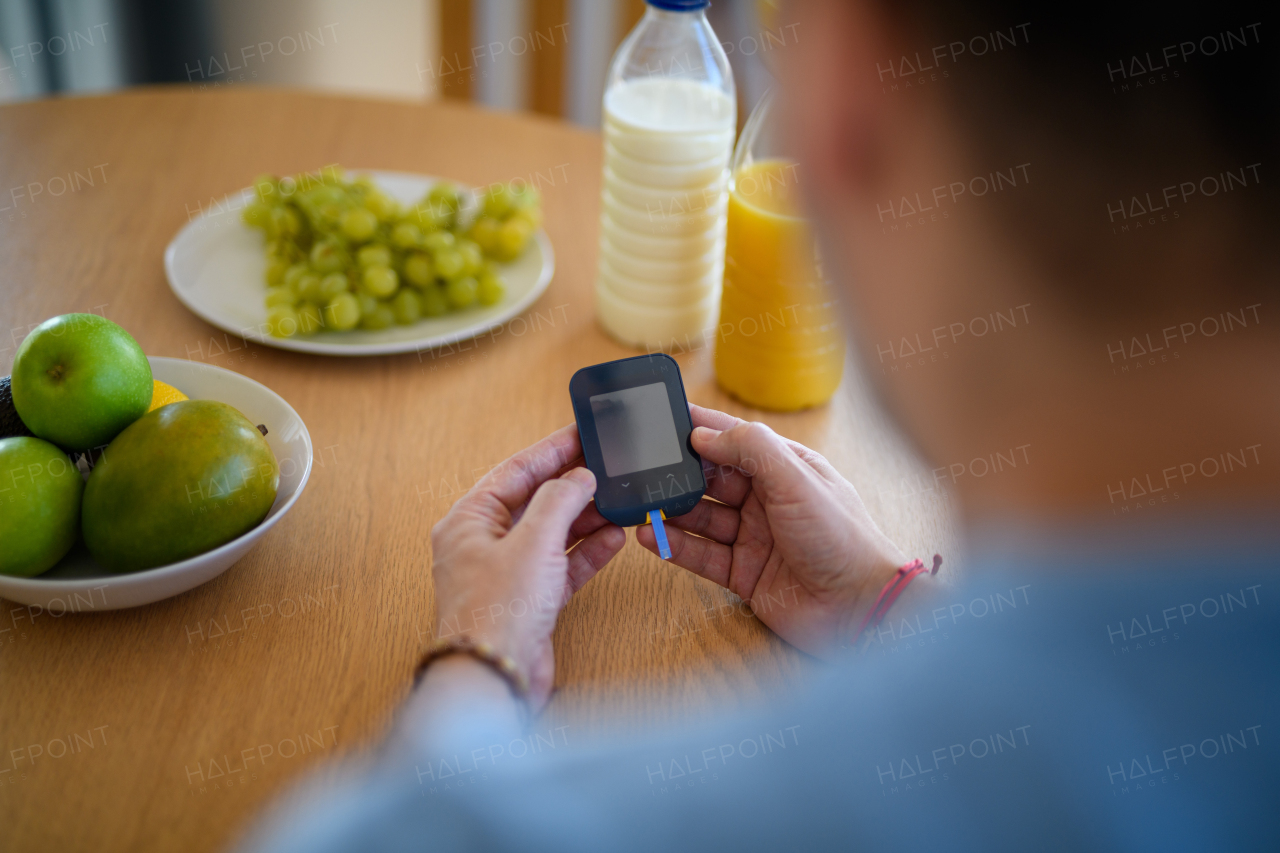 Close up of diabetic man holding blood glucose meter to check blood sugar.