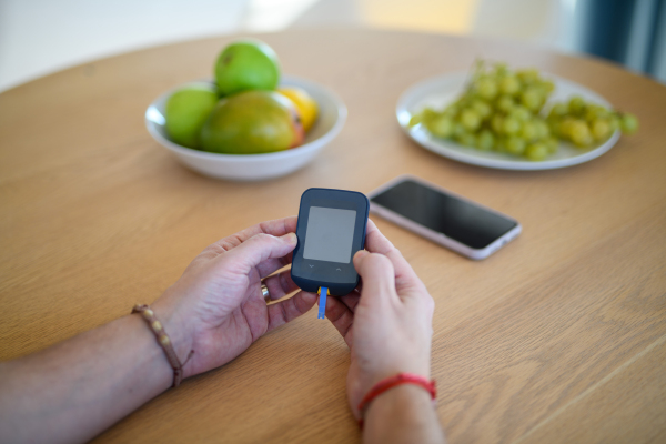 Close up of diabetic man holding blood glucose meter to check blood sugar.