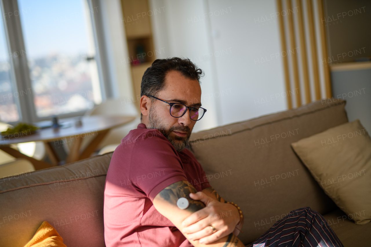 Portrait of handsome man checking his CGM sensor on arm.