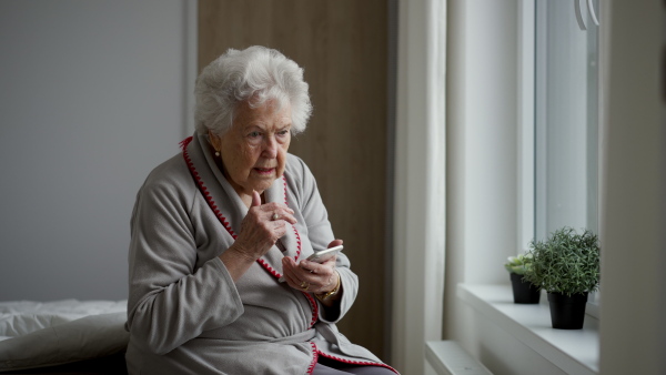 A horrified senior woman scrolling her smartphone. Phone scams on elderly people.