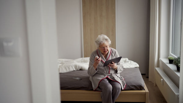 Senior woman reading a medication leaflet and dosage instructions on tablet. Managing medication for seniors.