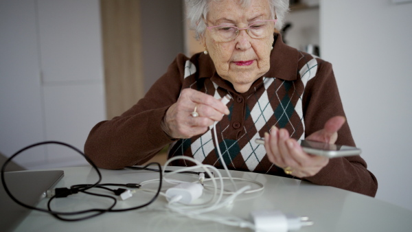 Confused senior woman searching for the right charger for her smartphone.