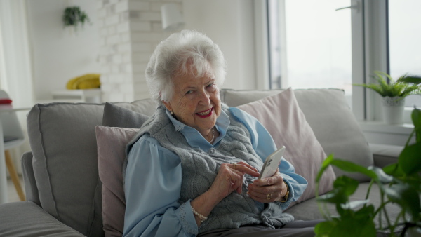 A video of senior woman sitting on sofa and texting. Elderly people using smartphones.