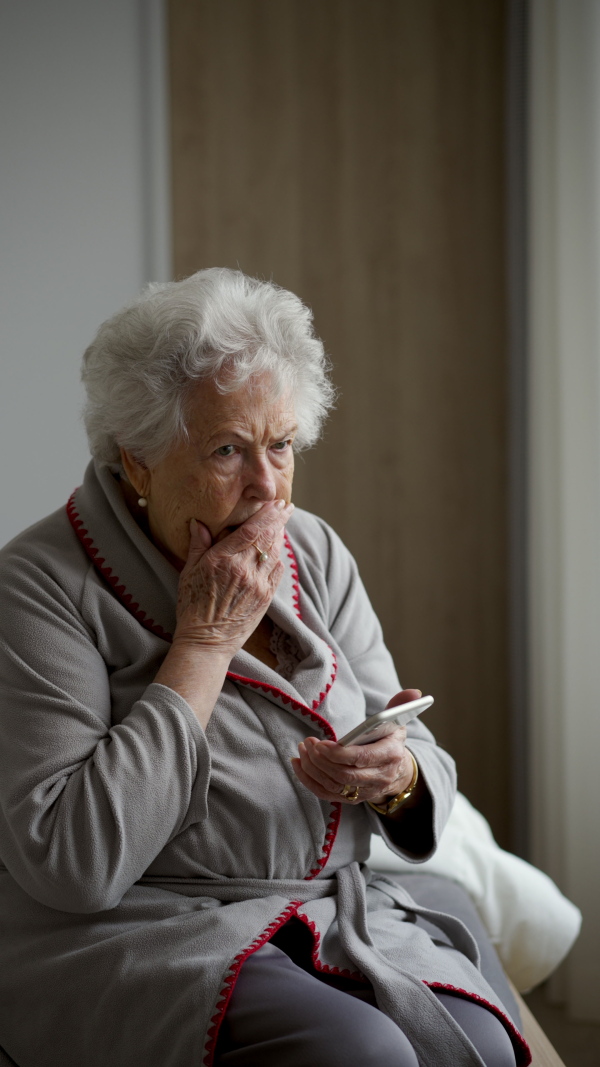 A horrified senior woman scrolling her smartphone. Phone scams on elderly people.