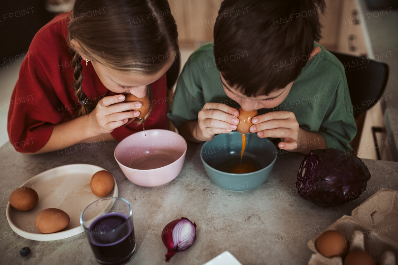 Siblings preparing egshells for easter egg decorating. Blowing out eggs. Kids craft project.