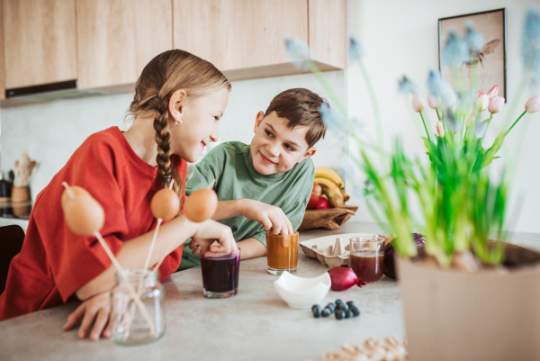 Siblings using natural dyes to decorate egshells for easter egg decorating. Kids craft project.