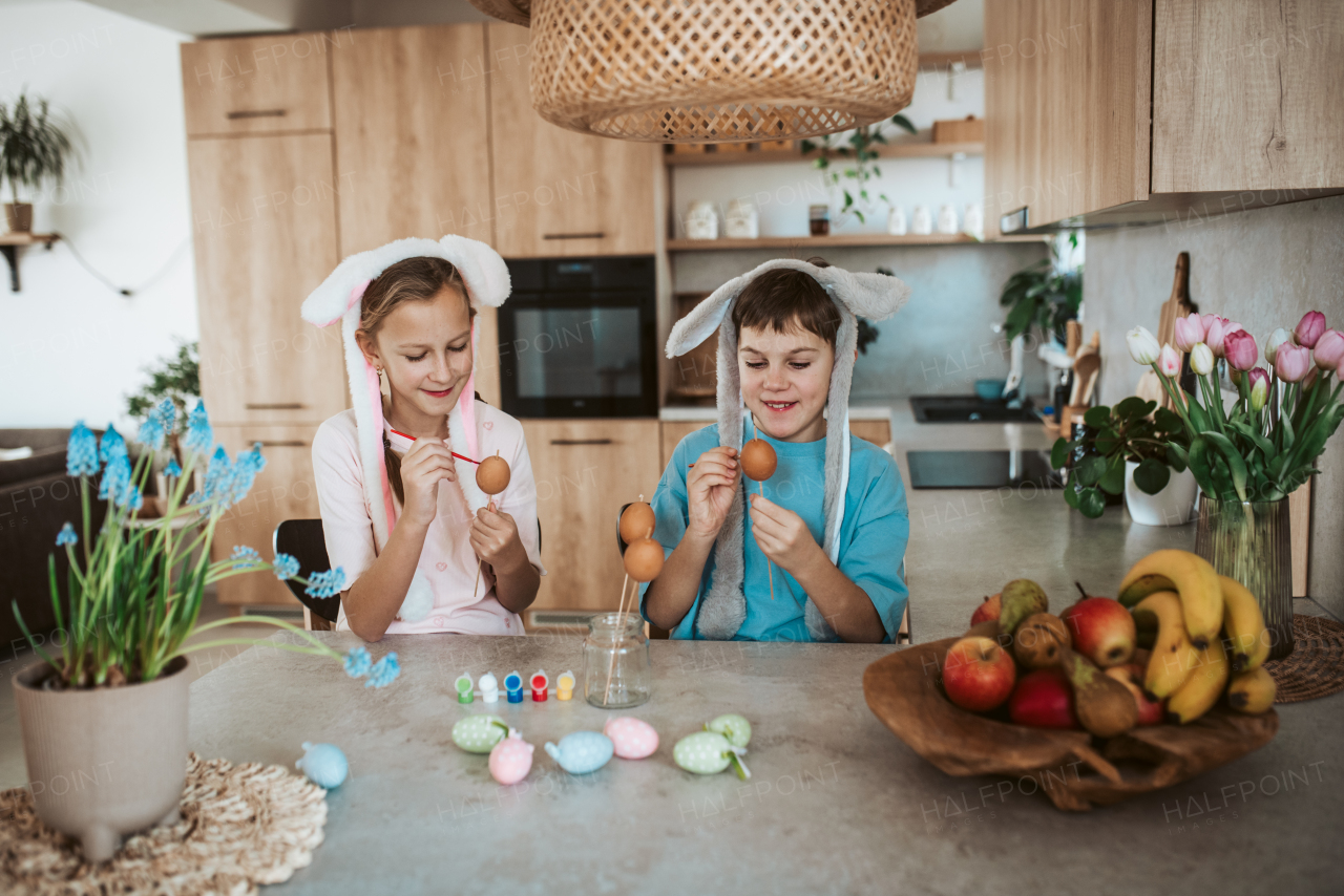 Girl and boy paiting eggs for easter. Siblings decorate egshells for easter egg decorating.