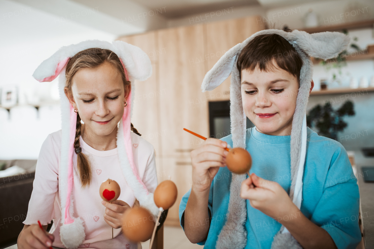 Girl and boy paiting eggs for easter. Siblings decorate egshells for easter egg decorating.