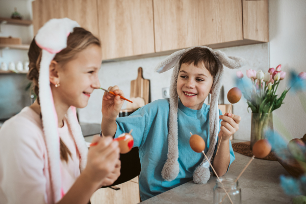 Siblings having fun while paiting eggs for easter. Easter egg decorating.