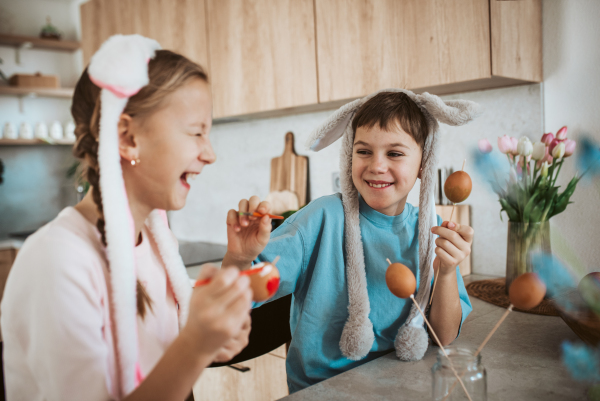 Girl and boy paiting eggs for easter. Siblings decorate egshells for easter egg decorating.