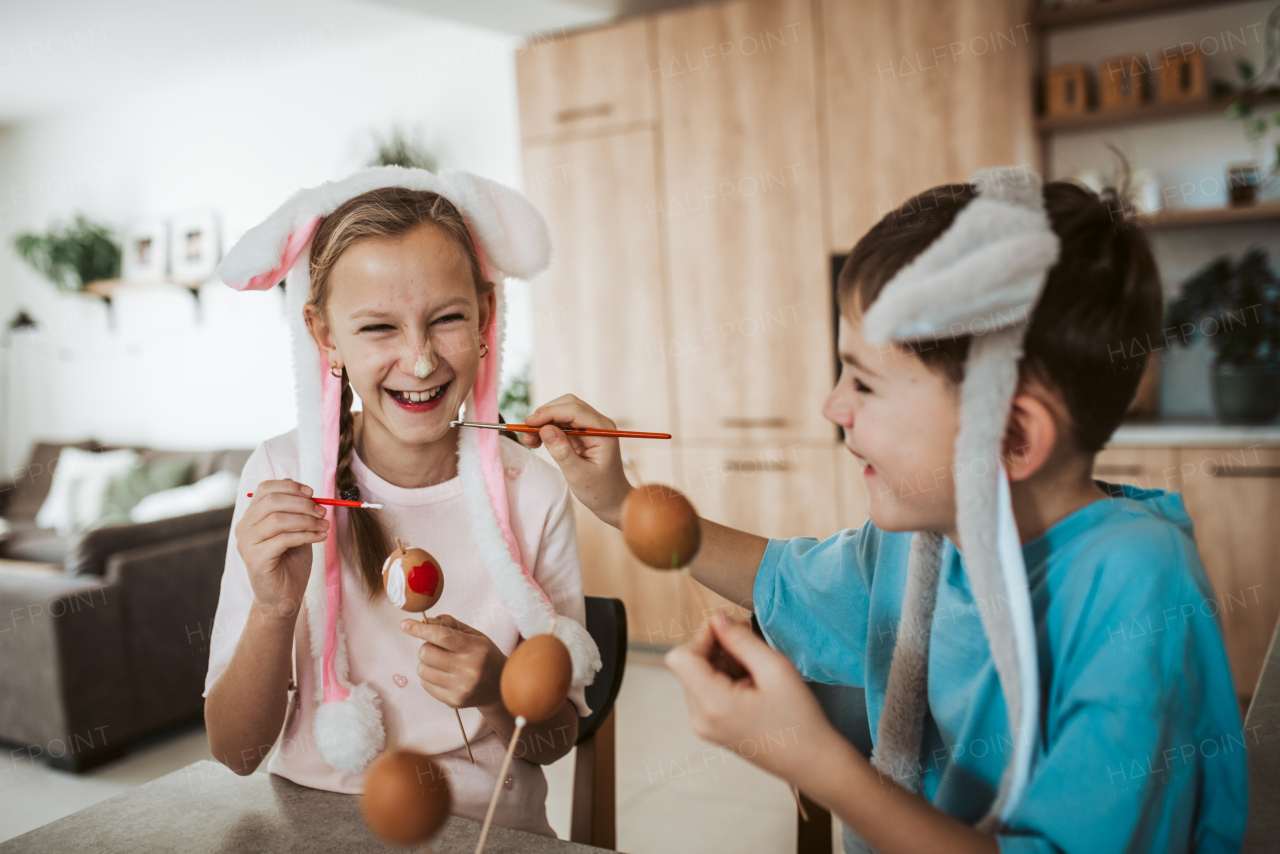 Siblings having fun while paiting eggs for easter. Easter egg decorating.