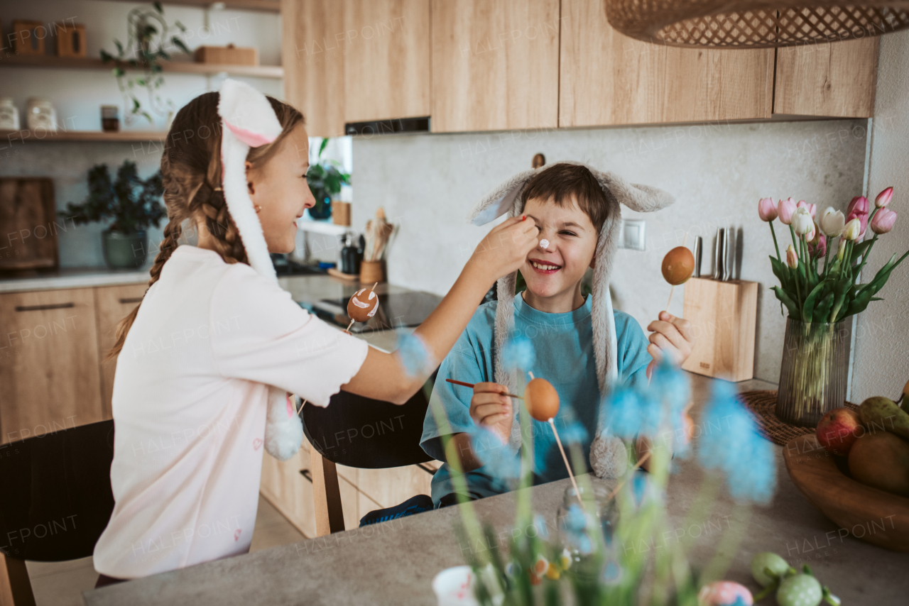 Girl and boy paiting eggs for easter. Siblings decorate egshells for easter egg decorating.