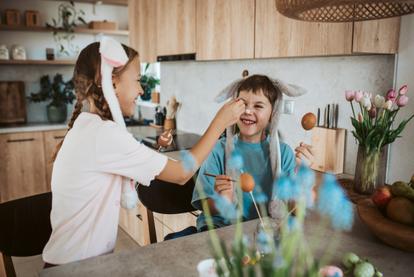 Girl and boy paiting eggs for easter. Siblings decorate egshells for easter egg decorating.