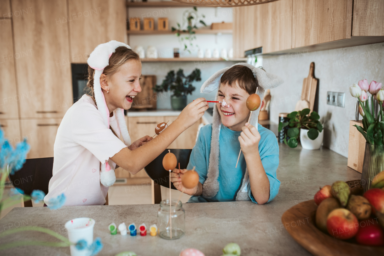 Girl and boy paiting eggs for easter. Siblings decorate egshells for easter egg decorating.