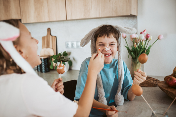 Siblings having fun while paiting eggs for easter. Easter egg decorating.