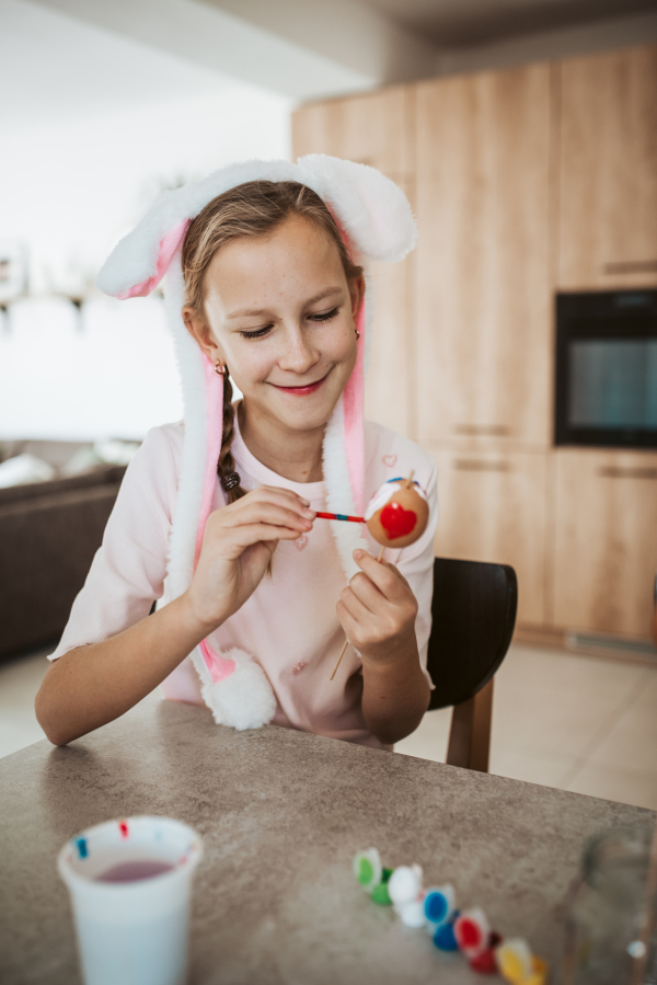 Girl with bunny ears paiting eggs for easter egg decorating.