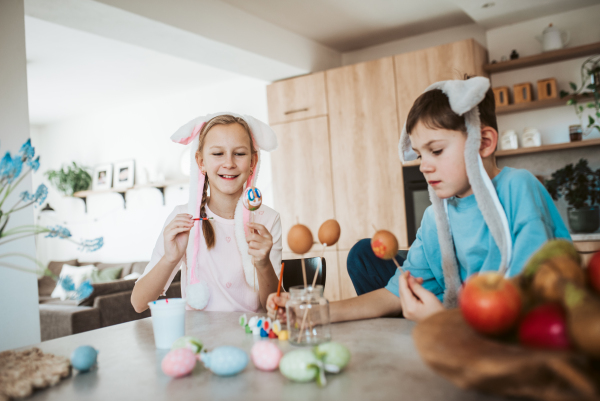 Girl and boy paiting eggs for easter. Siblings decorate egshells for easter egg decorating.