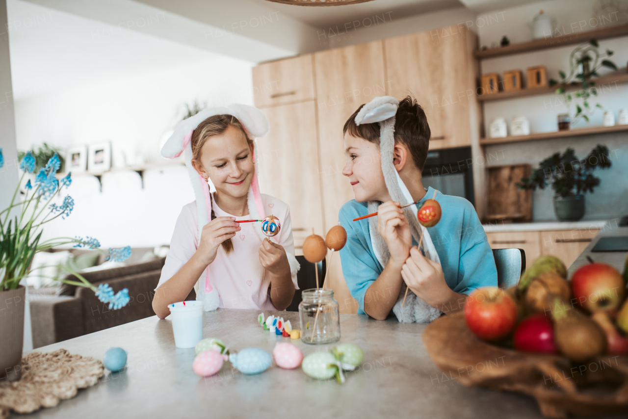 Girl and boy paiting eggs for easter. Siblings decorate egshells for easter egg decorating.