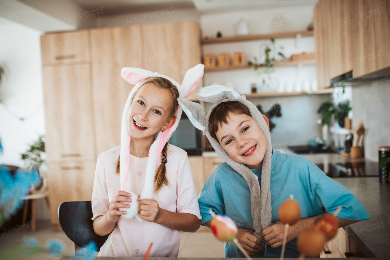 Girl and boy paiting eggs for easter, wearing bunny ears. Siblings decorate egshells for easter egg decorating.