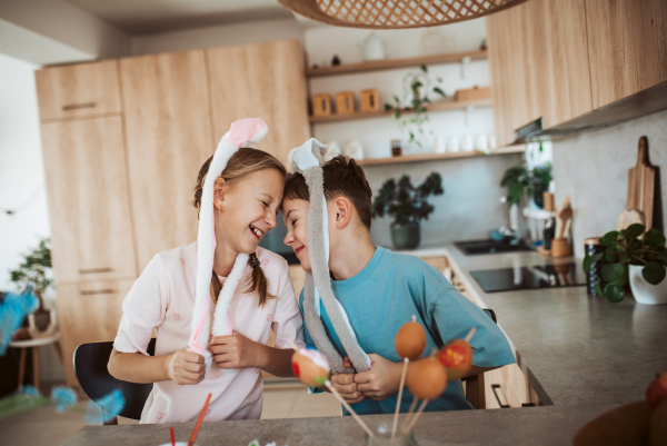 Girl and boy paiting eggs for easter. Siblings decorate egshells for easter egg decorating.