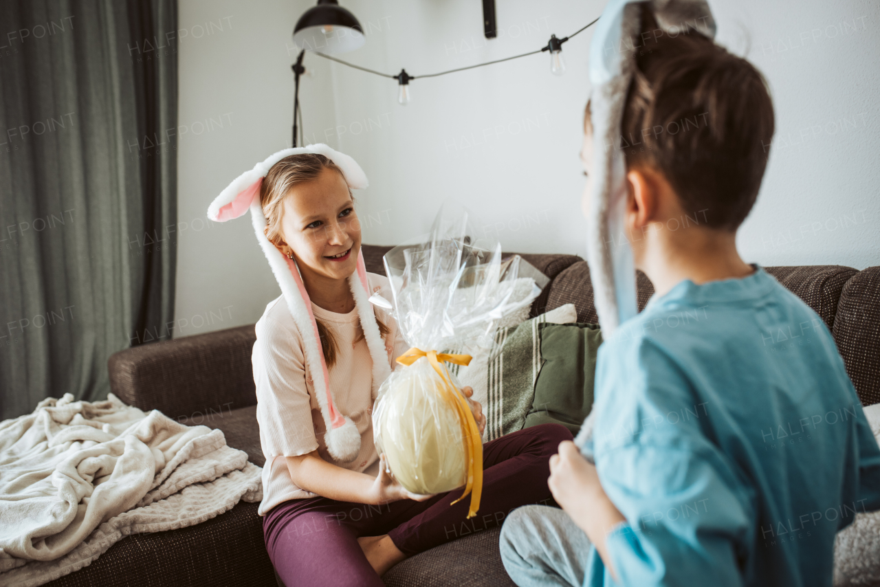 Little girl gifting a large Easter egg to young boy.