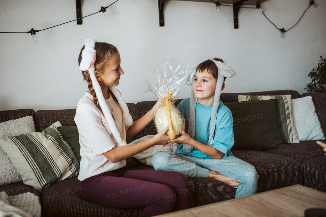 Little girl gifting a large Easter egg to young boy.