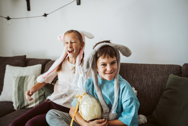 Young girl gifting a large Easter egg to her brother.