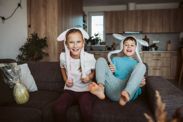 Brother and sister wearing bunny ear headbands. Siblings celebrating Easter.