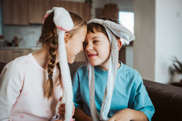 Brother and sister wearing bunny ear headbands. Siblings celebrating Easter.