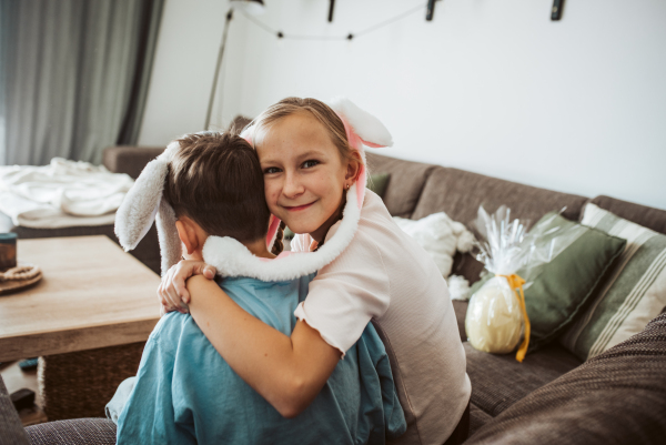 Brother and sister wearing bunny ear headbands hugging. Siblings celebrating Easter.