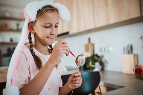 Girl with bunny ears paiting eggs for easter egg decorating.