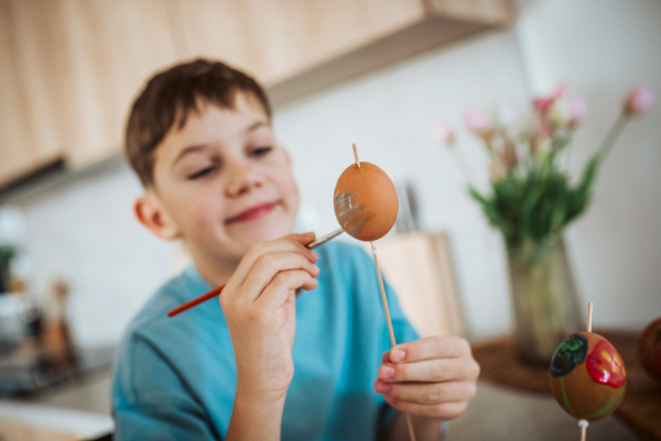 Smiling boy paiting eggs for easter egg decorating.