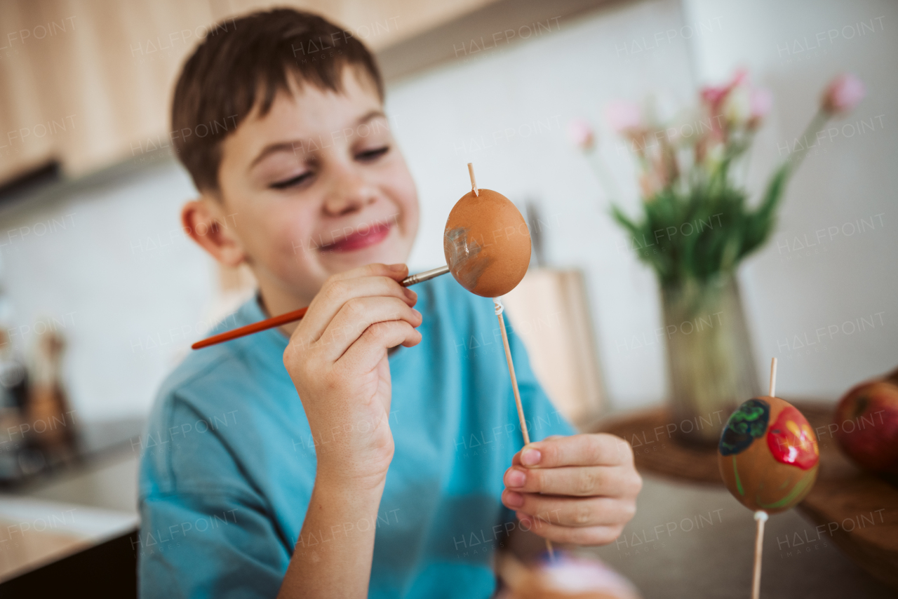 Smiling boy paiting eggs for easter egg decorating.