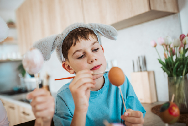 Smiling boy paiting eggs for easter egg decorating.