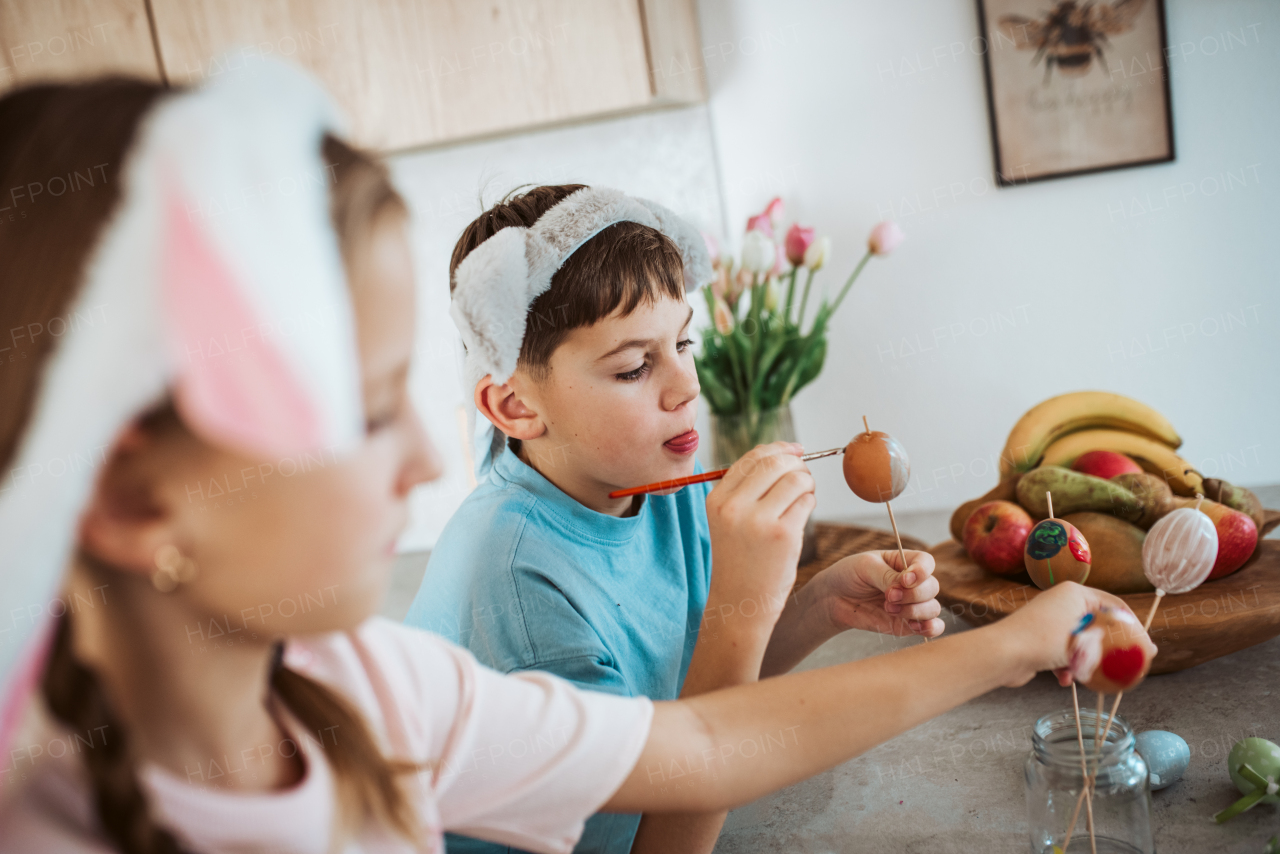 Girl and boy paiting eggs for easter. Siblings decorate egshells for easter egg decorating.