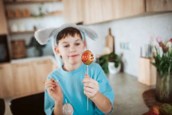 Smiling boy paiting eggs for easter egg decorating.